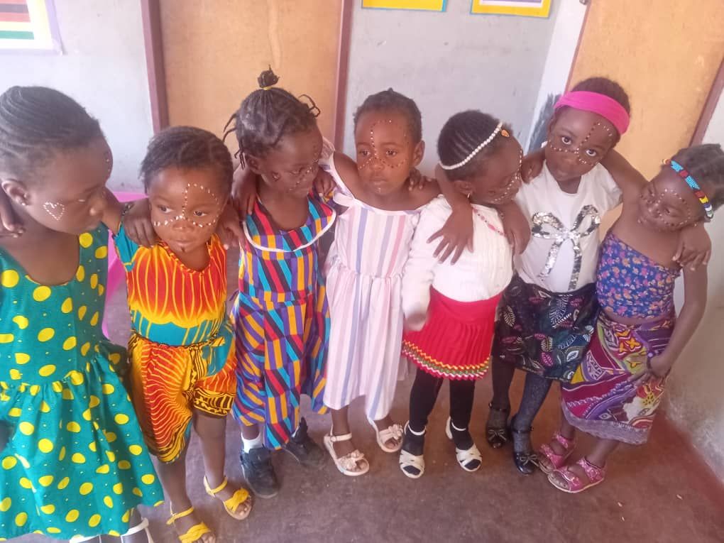 Girls in colourful traditional outfits with arms around each other on Africa Day