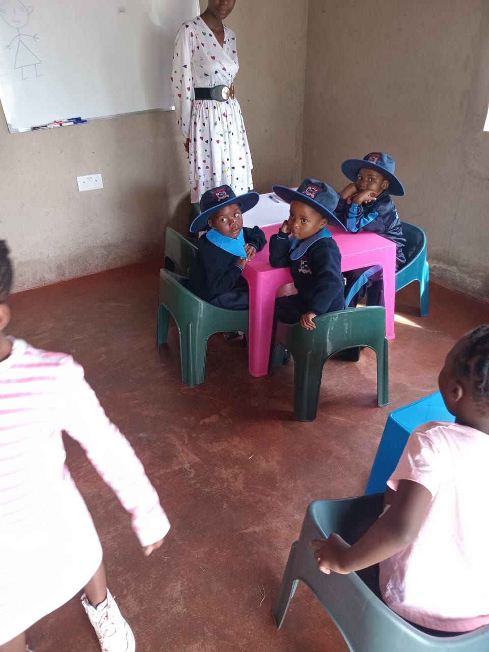 A teacher with learners around a table in the Bright Beginners classroom