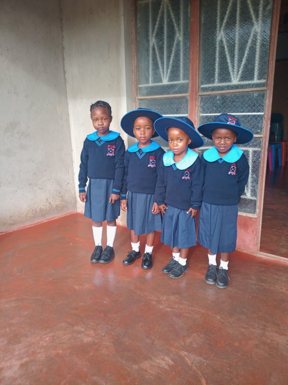 Four Bright Beginners learners smiling in their navy and sky-blue school uniforms