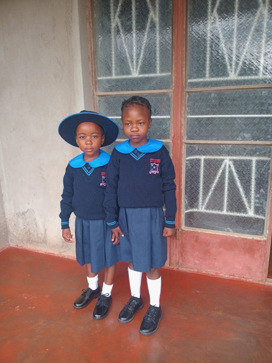 Two learners in uniform holding hands